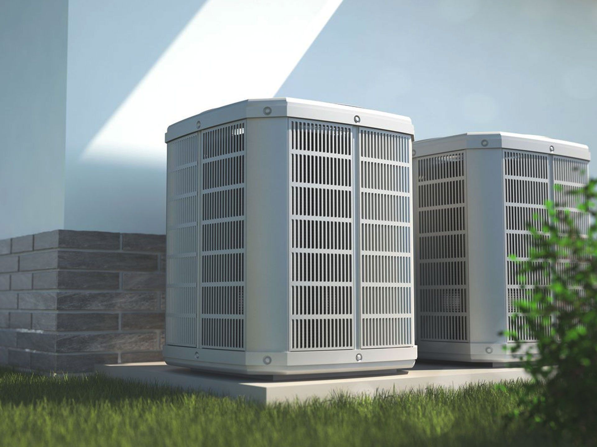 Two outdoor HVAC condenser units beside a house wall in bright sunlight