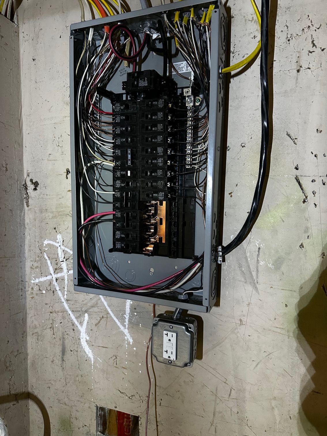 Open electrical breaker panel with exposed wiring mounted on a wall