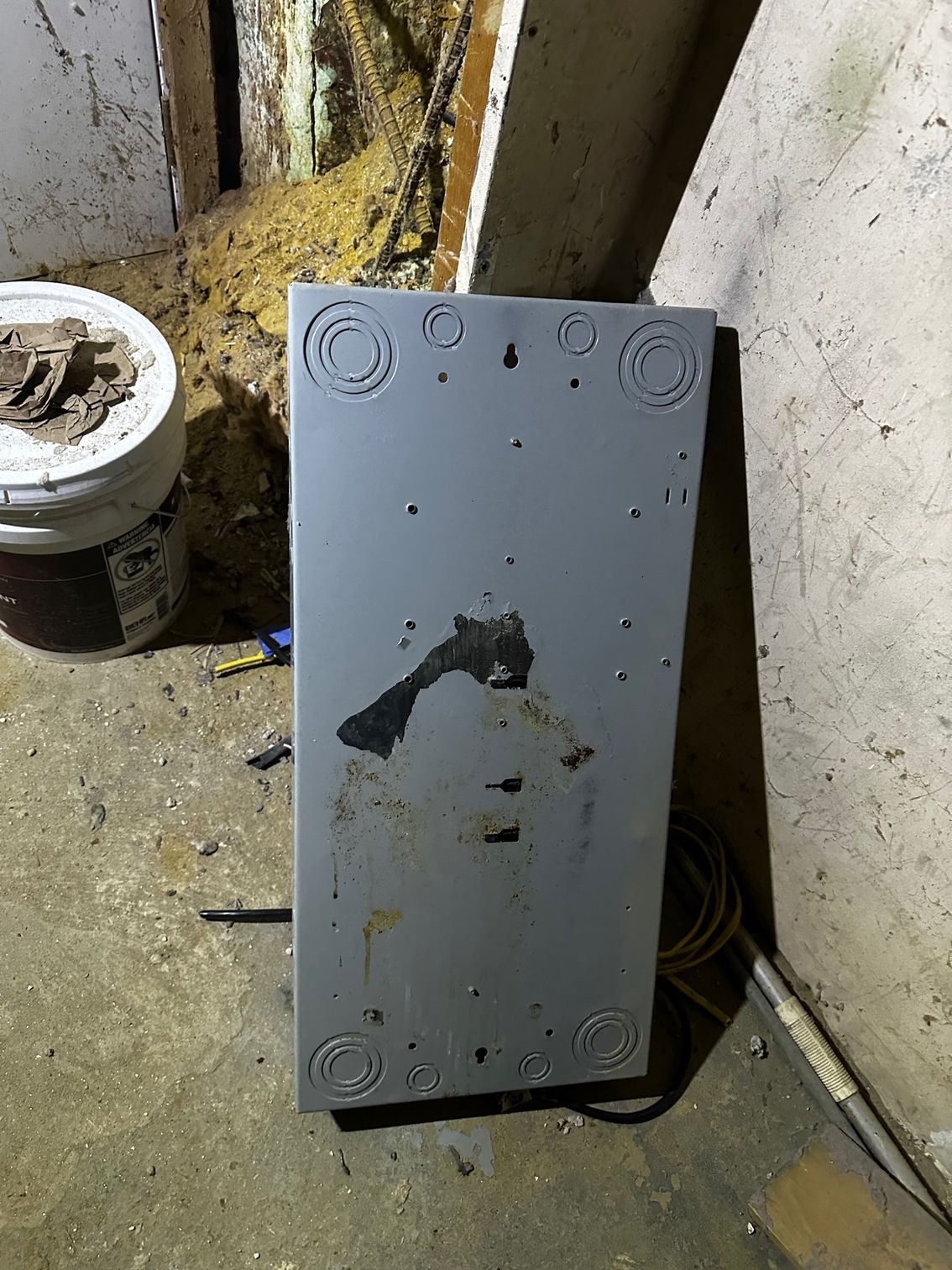 Gray metal panel leaning against a dirty wall in a basement-like corner.