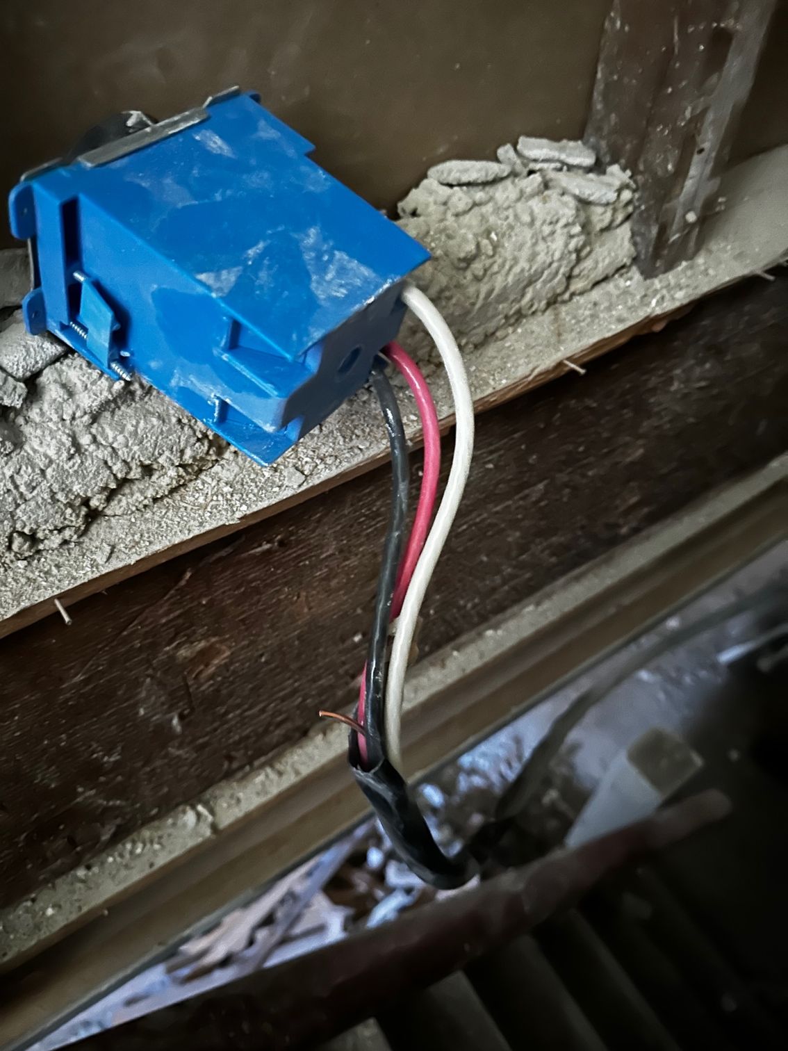 Blue electrical connector with red, white, and black wires mounted inside a dusty metal panel.